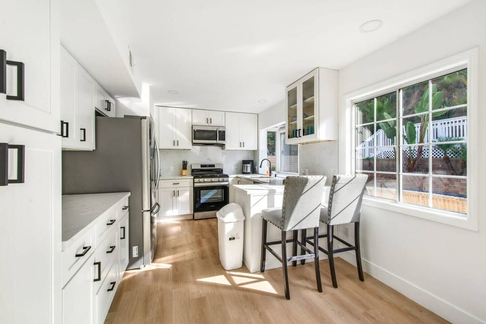 Fully stocked kitchen with stainless steel appliances, coffee maker, and barstool seating for 2.