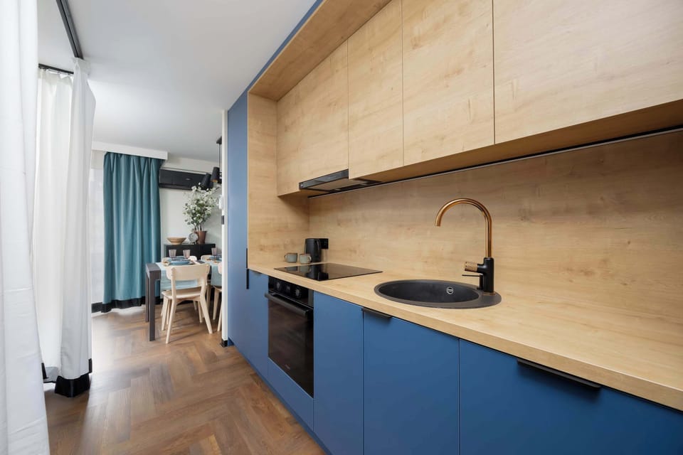 The kitchen in shades of blue and natural wood creates a modern yet warm space for preparing meals.