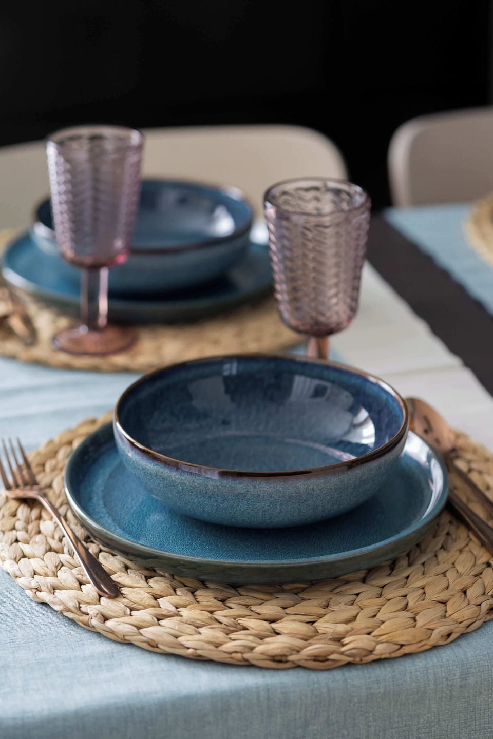 A neatly set table with blue tableware invites you to share a meal in an elegant, intimate setting.