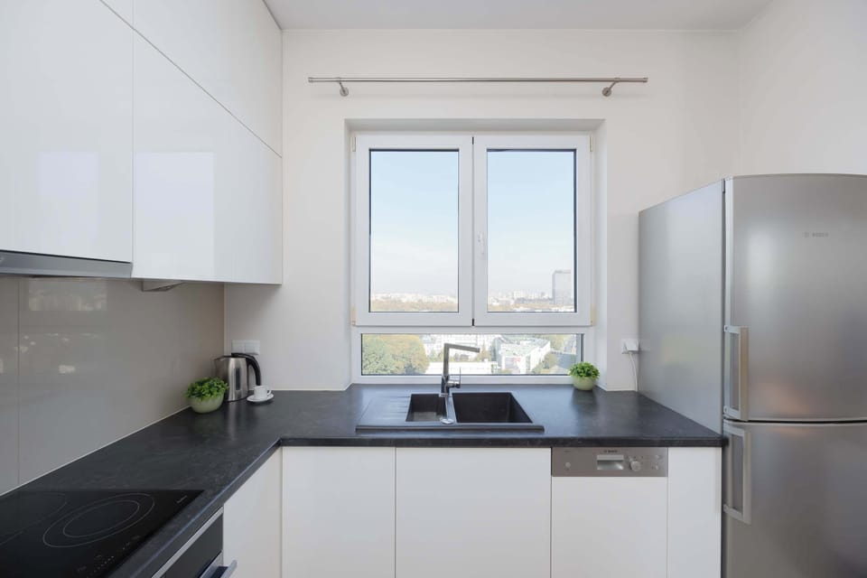 Modern kitchen with white cabinets, built-in oven, and sleek countertops.