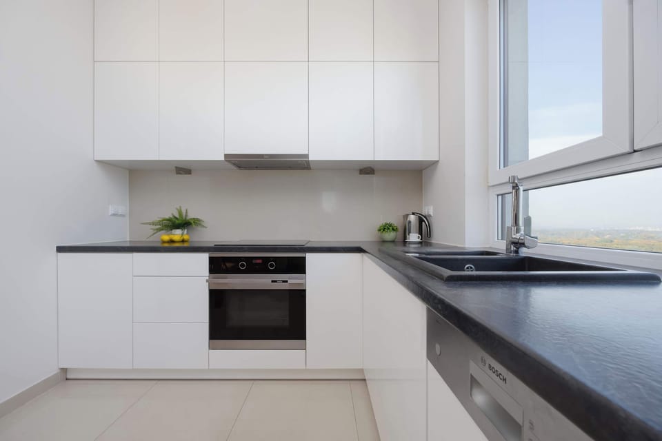 Modern kitchen with white cabinets, built-in oven, and sleek countertops.