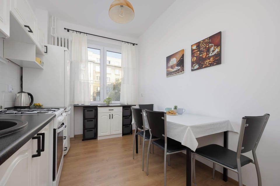 A different view of the kitchen reveals a harmonious blend of bright furniture and wooden flooring that brings freshness to the space.