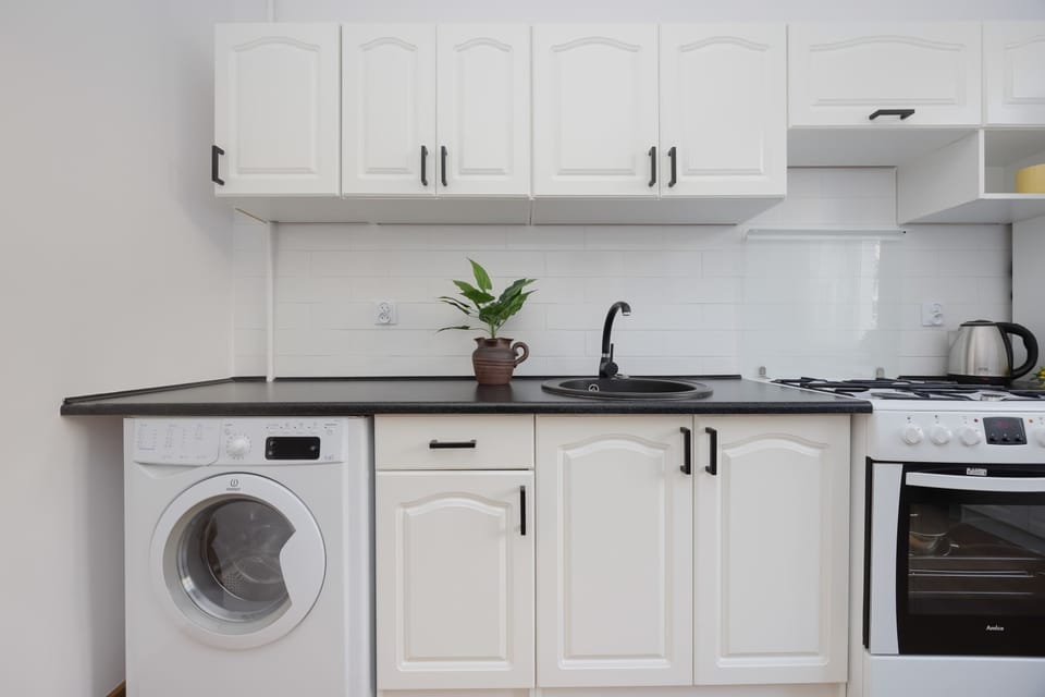 A bright kitchen with white cabinets, a washing machine and a practical countertop provides comfort for everyday meal preparation.