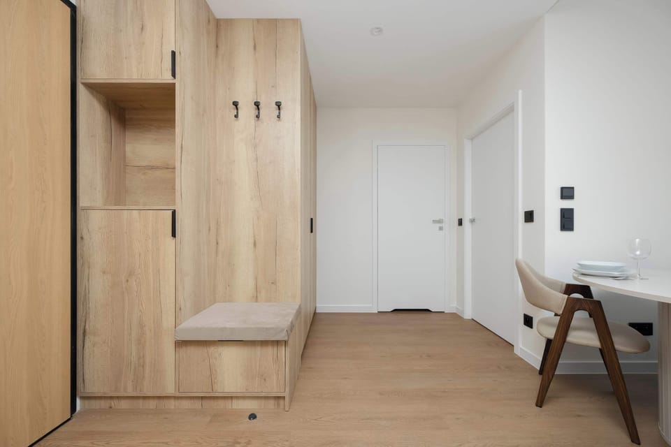 A hallway with neutral-colored walls and a set of wooden doors.