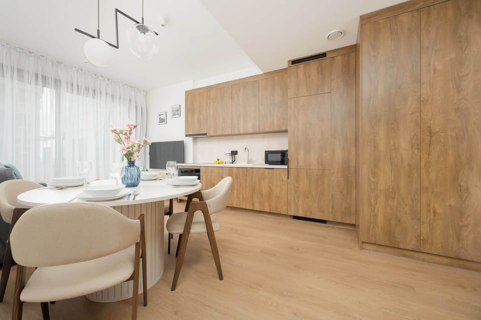 A kitchen space featuring light wood cabinetry, a double sink, and a white countertop with kitchen essentials.