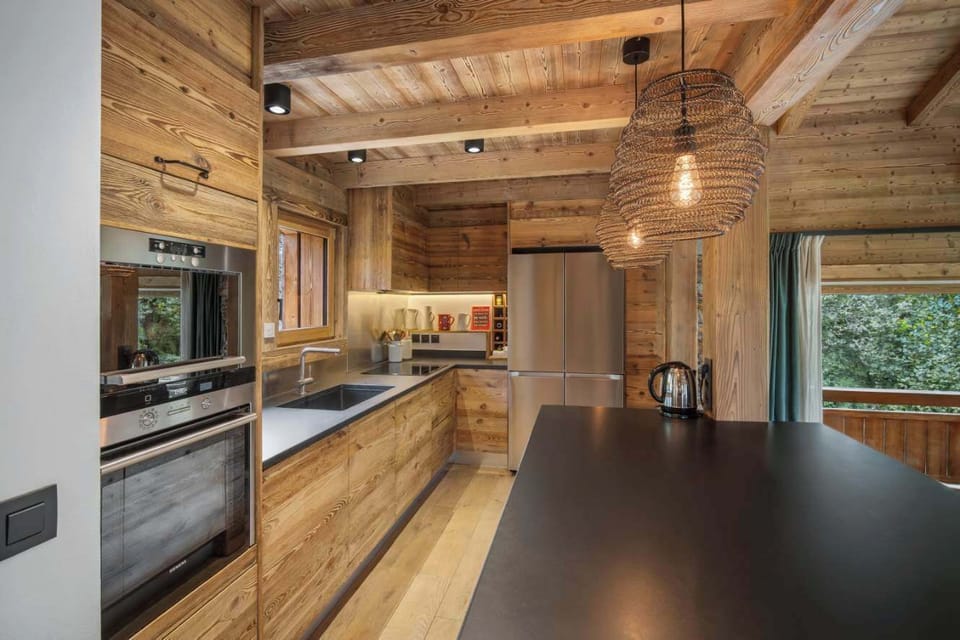 Fully equipped kitchen with modern appliances and wooden finishes.
– Includes coffee machine, raclette, toaster, oven, microwave, and all vacation rental essentials.