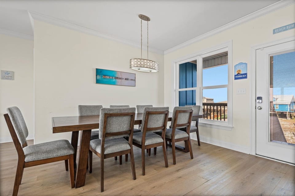Gather around this spacious dining table where family meals become cherished memories, with coastal views beyond.
