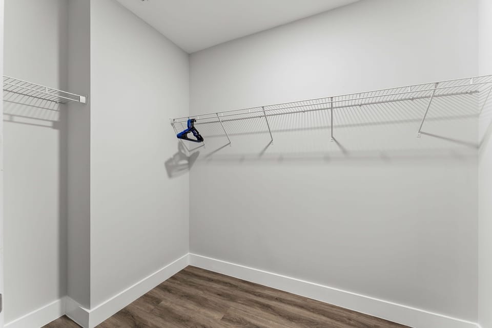 spacious walk-in closet with wire shelving and wood flooring
