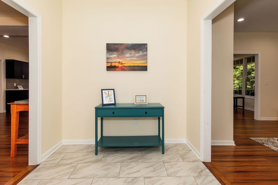 The welcoming entryway sets a warm tone with coastal-inspired artwork above a teal console table, inviting you into this thoughtfully designed retreat.