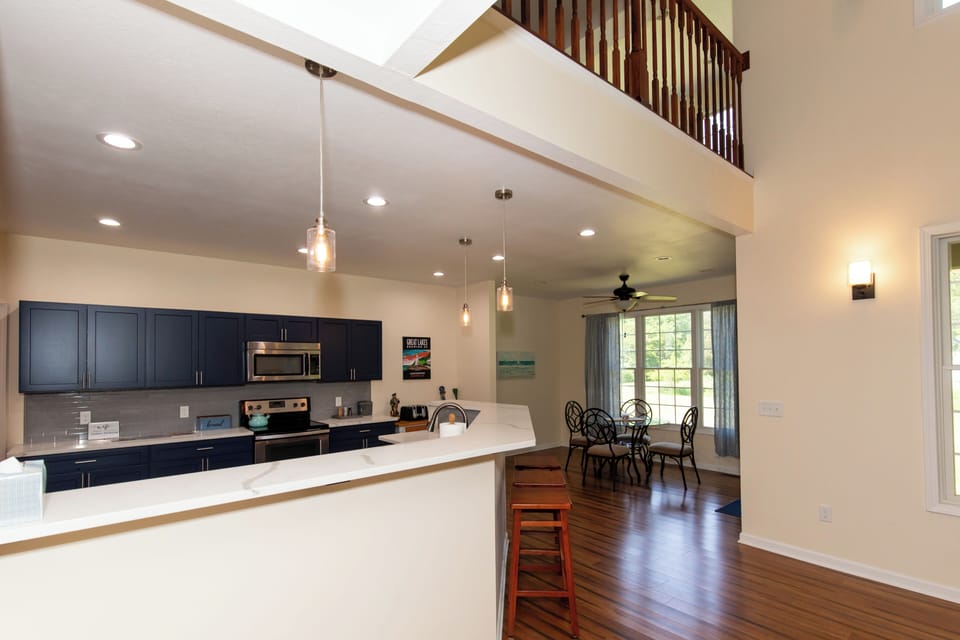 Step into this bright, open-concept living space where soaring ceilings and natural light create an inviting atmosphere. The modern kitchen with sleek cabinetry flows seamlessly into your dining area, perfect for gathering and making memories.