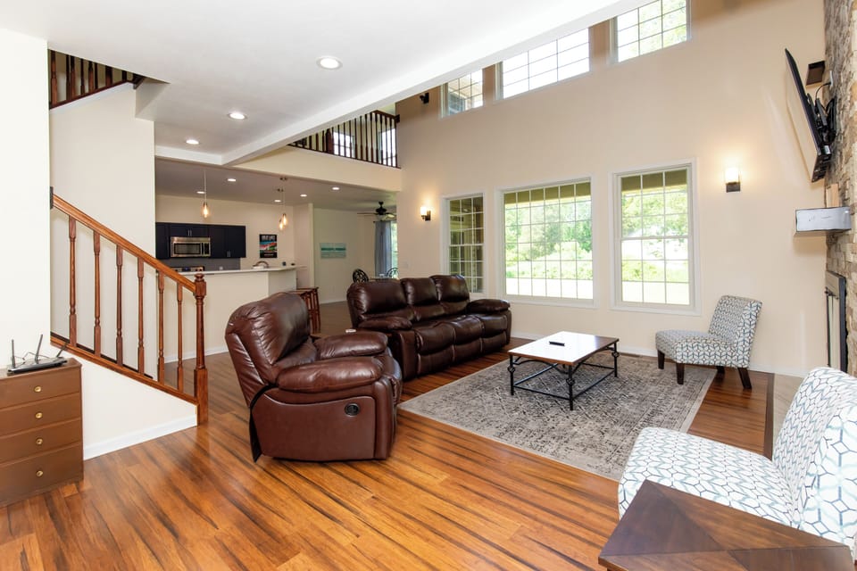 Unwind in your spacious living room, where soaring ceilings and natural light create an airy retreat. Sink into plush leather seating, gather around the coffee table, and enjoy the open flow to your fully equipped kitchen.