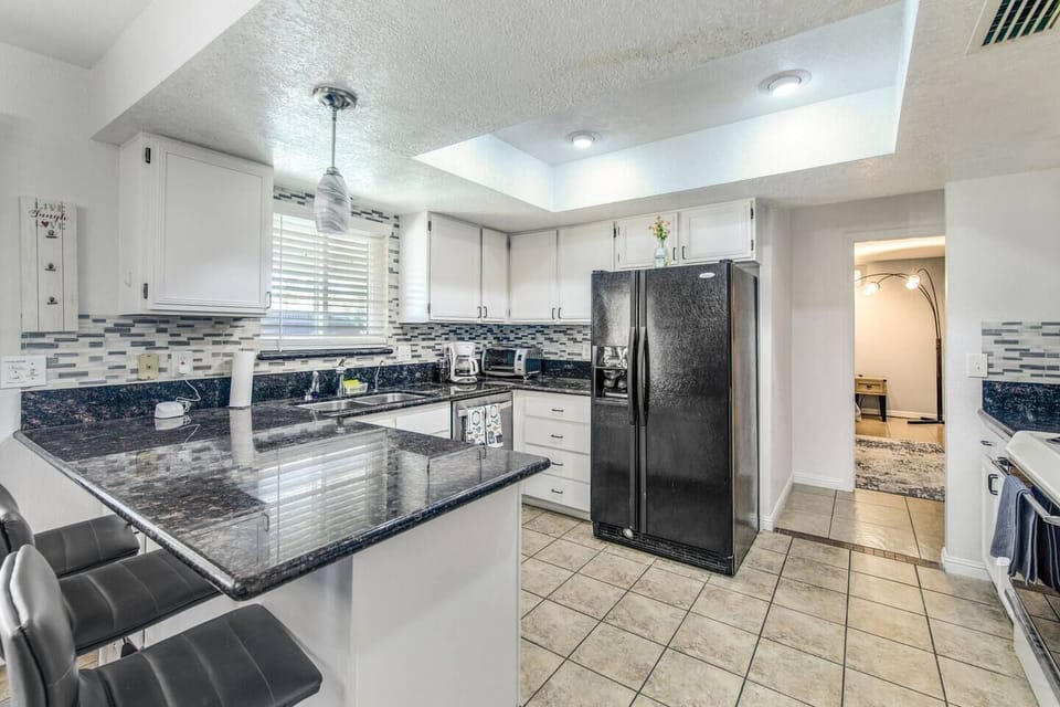 Modern kitchen featuring all supplies, seating for 3 at the bar, and coffee essentials.