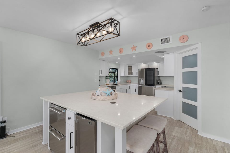 Center island features not only seating but also a beverage fridge and an ice maker.