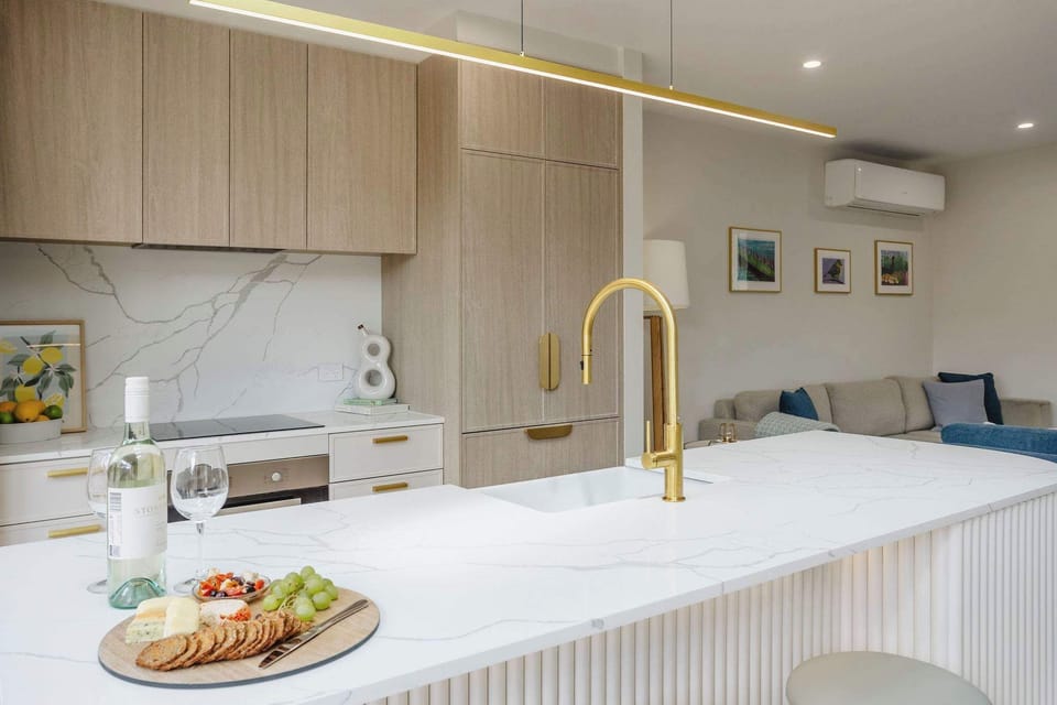 Modern kitchen design with crisp white finishes and warm light brown cupboards, complemented by a counter, stove and oven for both style and function