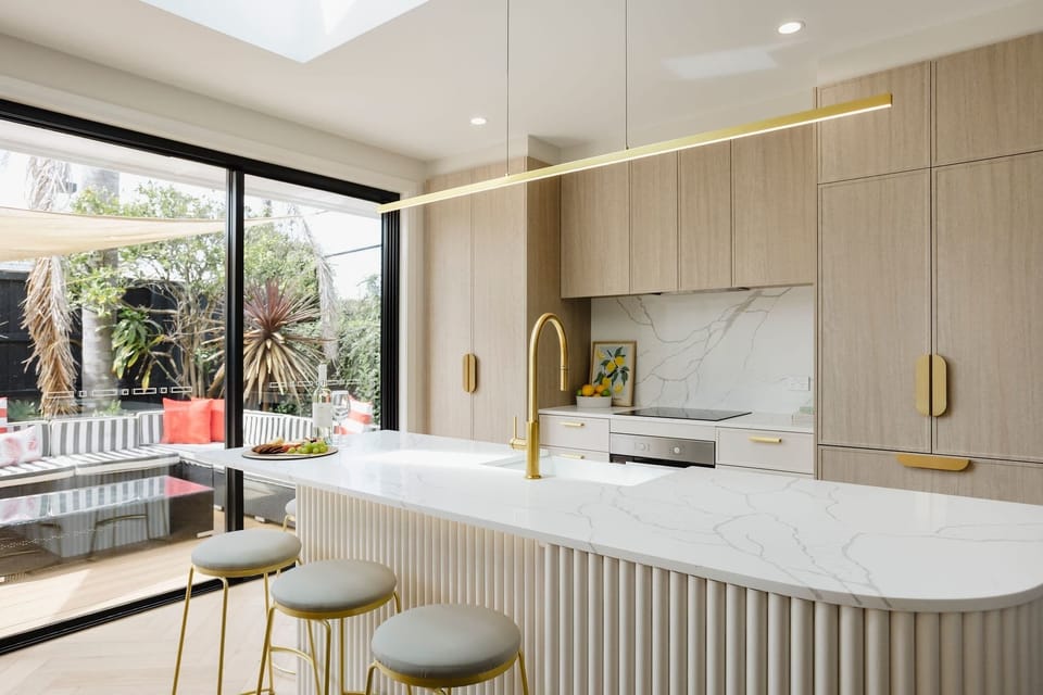 Modern kitchen design with crisp white finishes and warm light brown cupboards, complemented by a counter, stove and oven for both style and function