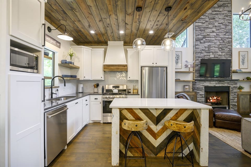 A fully equipped, modern kitchen with a rustic touch, stainless steel appliances, and a unique island.
