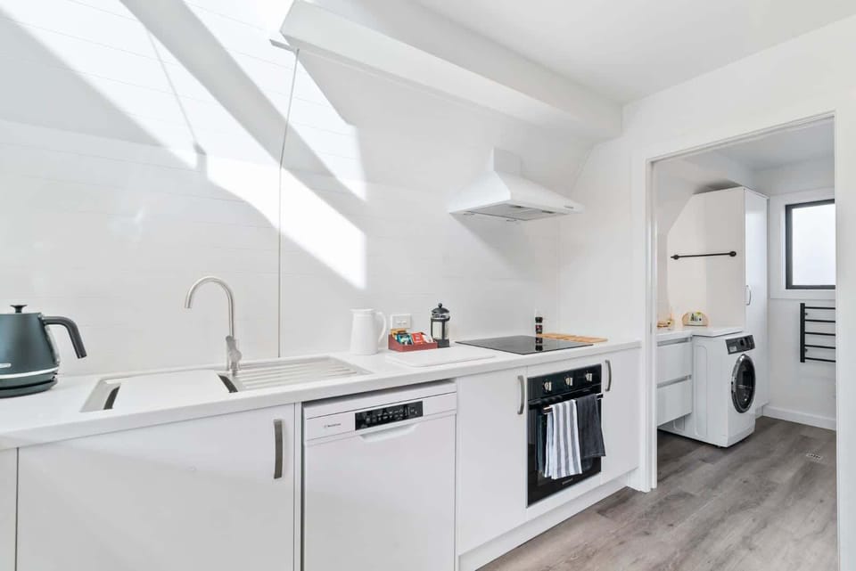Fully equipped kitchen with oven, dishwasher, and laundry nook 