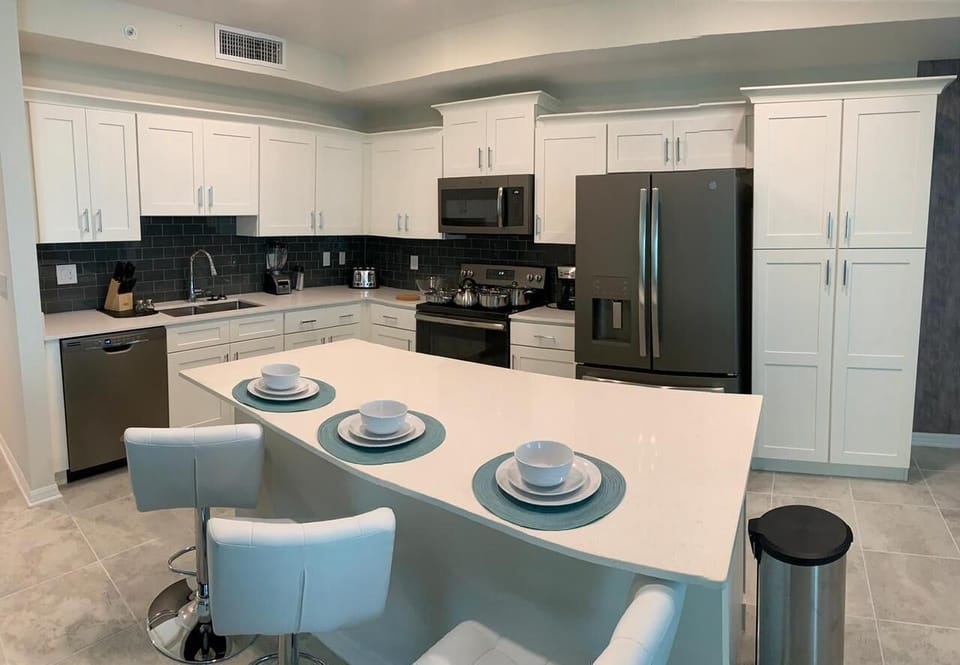 Modern kitchen with sleek white cabinets, stainless steel appliances, and a spacious island for shared meals