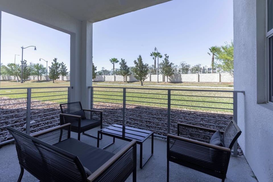 Step onto your private patio, where sleek black outdoor furniture complements the open layout. Enjoy the fresh breeze as you take in the lush greenery just beyond the glass railing, perfect for relaxation or casual conversations.