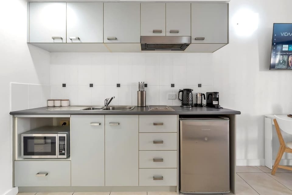The studio’s compact kitchenette includes a cooktop, mini fridge, microwave, and kettle—perfect for light meals or quick snacks.