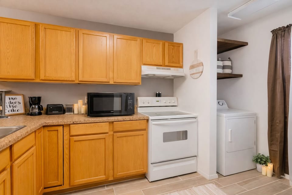 Bright, cozy kitchen w/ warm wood cabinets, white appliances, & place to unwind.