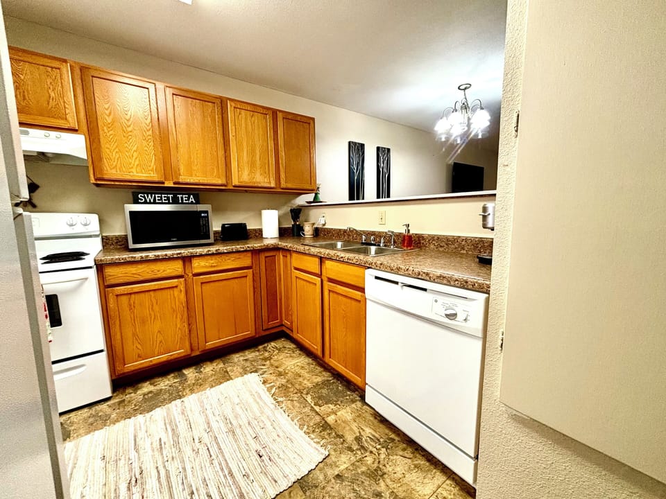 Bright, cozy kitchen w/ warm wood cabinets, white appliances, & place to unwind.