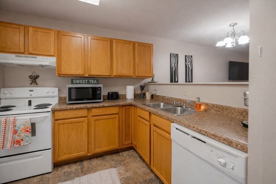 Bright, cozy kitchen w/ warm wood cabinets, white appliances, & place to unwind.