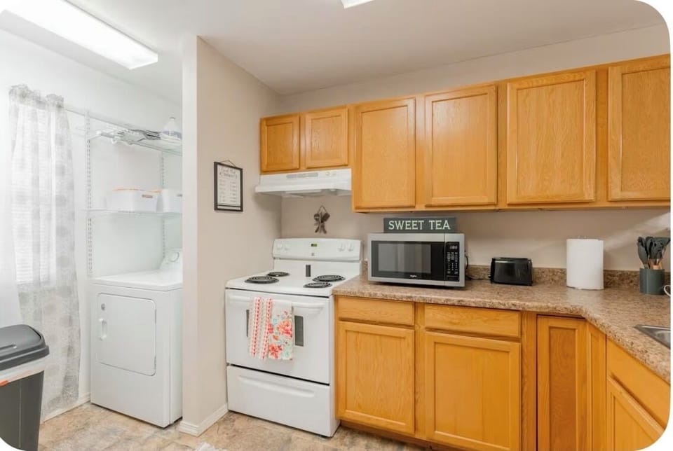 Bright, cozy kitchen w/ warm wood cabinets, white appliances, & place to unwind.
