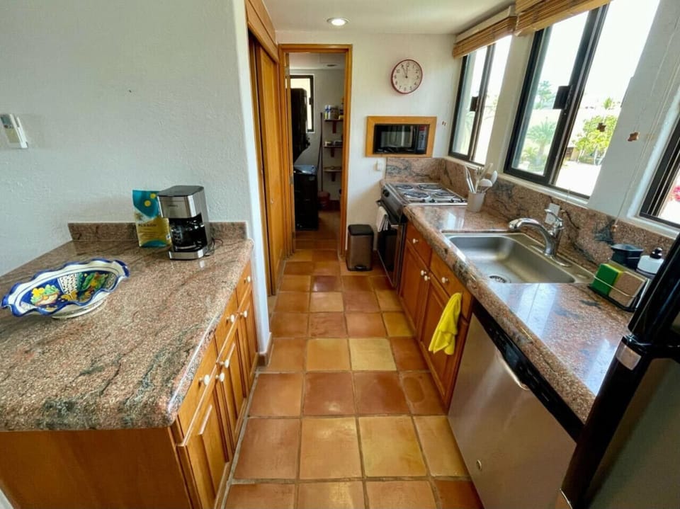 Compact kitchen with wood cabinets, granite counters, and natural light.