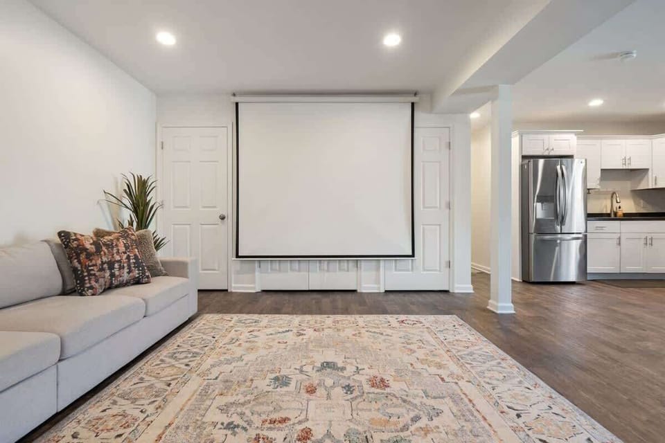 Open living and kitchen area with projector screen and stainless fridge