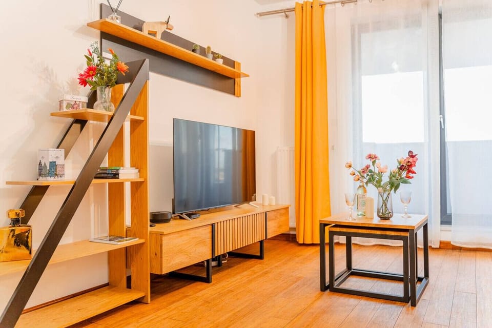 Living Area – Bright and stylish space with a comfy orange sofa, Smart TV, and direct access to the balcony | Book Now with RENTUJEMY.COM