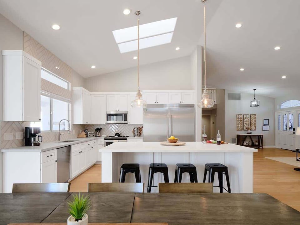 Fully equipped kitchen with stainless steel appliances, a sleek kitchen island with a breakfast bar for casual seating for 4, plus a large dining table for 8. (1st Floor)