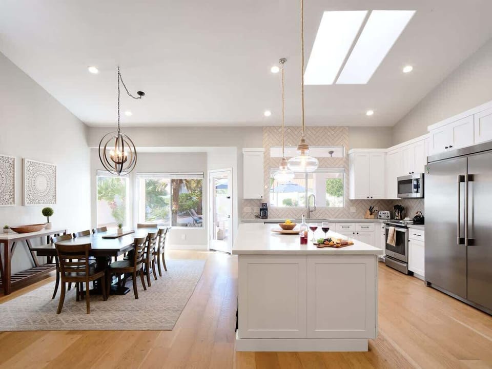 Fully equipped kitchen with stainless steel appliances, a sleek kitchen island with a breakfast bar for casual seating for 4, plus a large dining table for 8. (1st Floor)