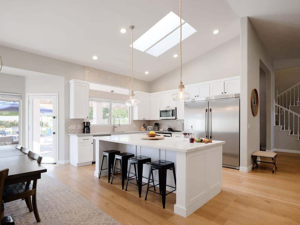 Fully equipped kitchen with stainless steel appliances, a sleek kitchen island with a breakfast bar for casual seating for 4, plus a large dining table for 8. (1st Floor)