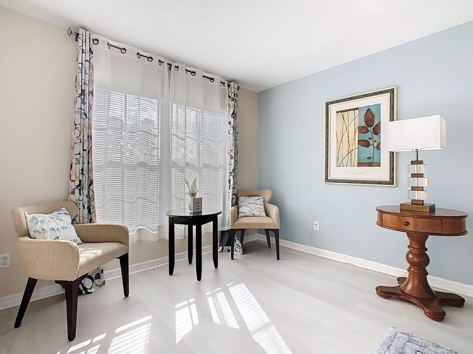 Bright sitting area with comfy chairs, windows, and chic decor — ideal for morning coffee or reading.