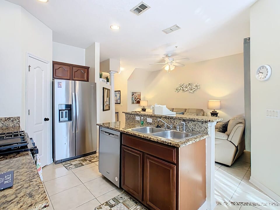 Stylish kitchen featuring granite countertops, stainless steel appliances, and an open layout connecting to the living room.