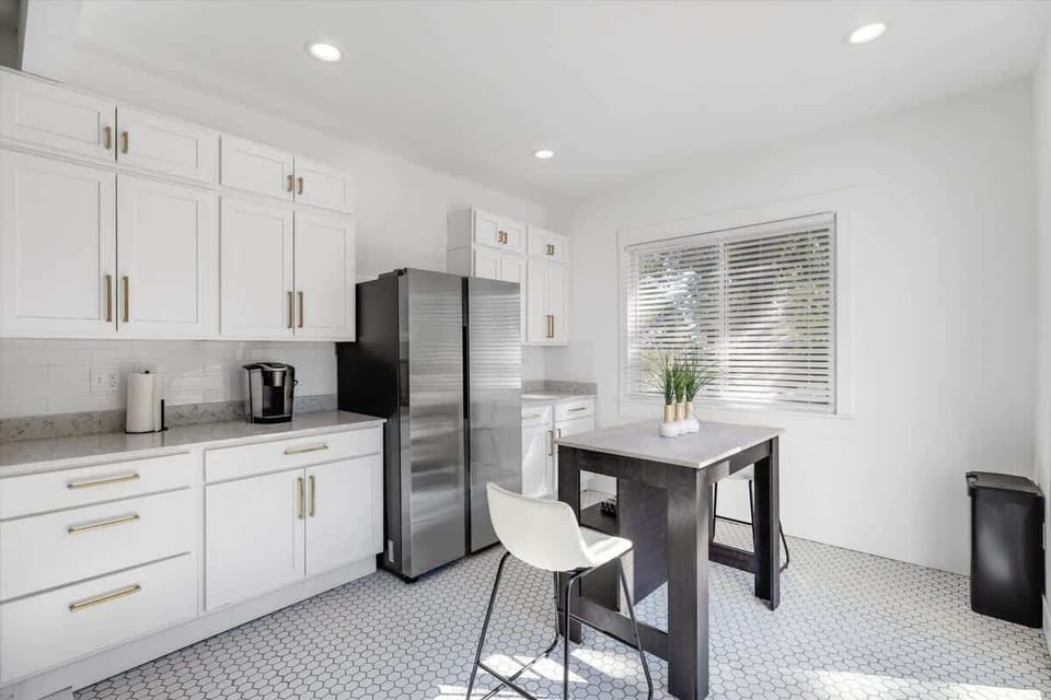 Bright kitchen with stainless fridge and breakfast table.