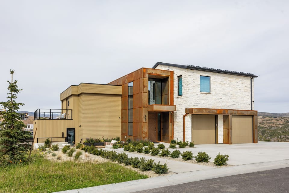 Striking modern exterior with warm wood accents, stone details, and a contemporary architectural profile. A stunning façade with exceptional curb appeal.