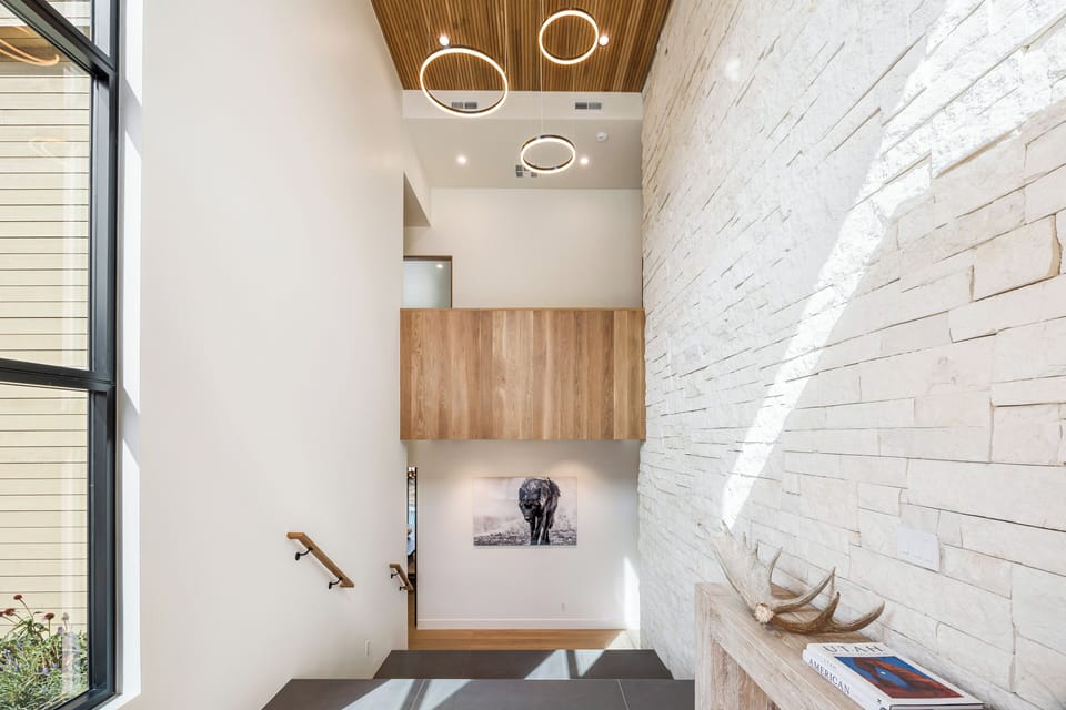 Striking two-story entryway with modern architectural details, natural stone walls, and statement lighting. A stunning first impression that sets the tone for the entire home.