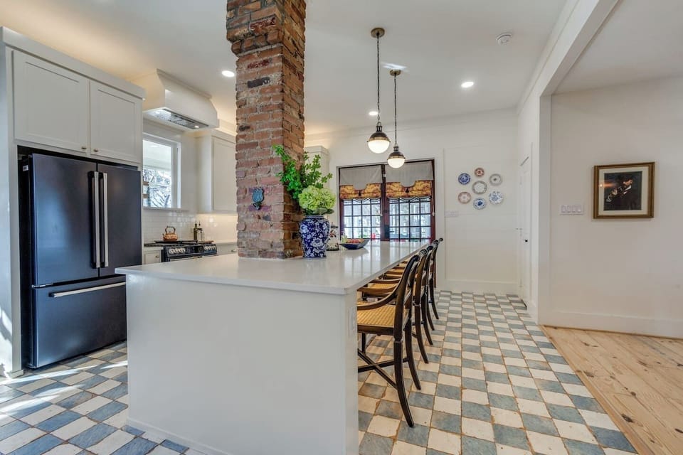 Expansive island overlooking the cozy breakfast nook, highlighted by the restored brick column and classic checkerboard flooring.