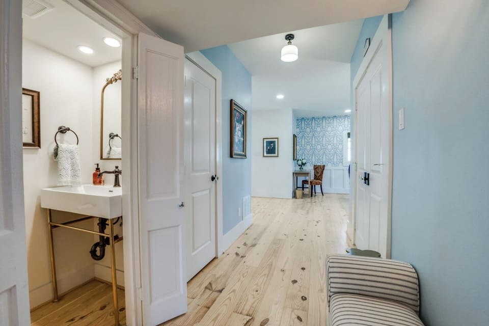 Charming half bathroom featuring elegant brass accents, a timeless pedestal-style sink, and a bright, inviting design—perfect for quick refreshes during your stay.