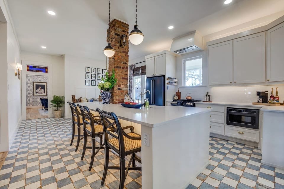 Light-filled gourmet kitchen featuring a spacious quartz island, exposed brick accents, and elegant designer lighting—where historic charm meets modern luxury.