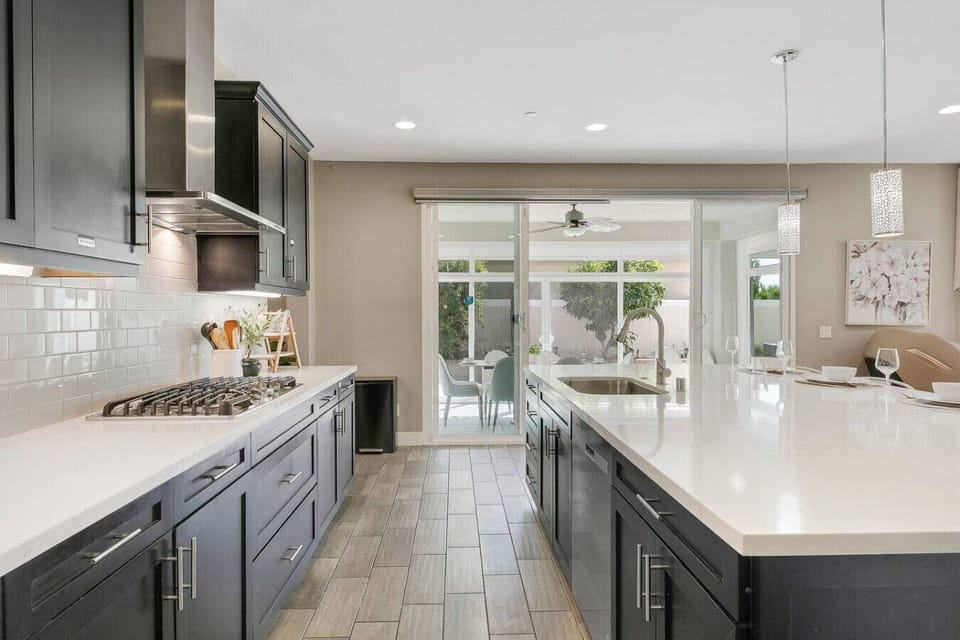 Contemporary kitchen featuring gas cooktop, island sink, and easy access to dining patio.