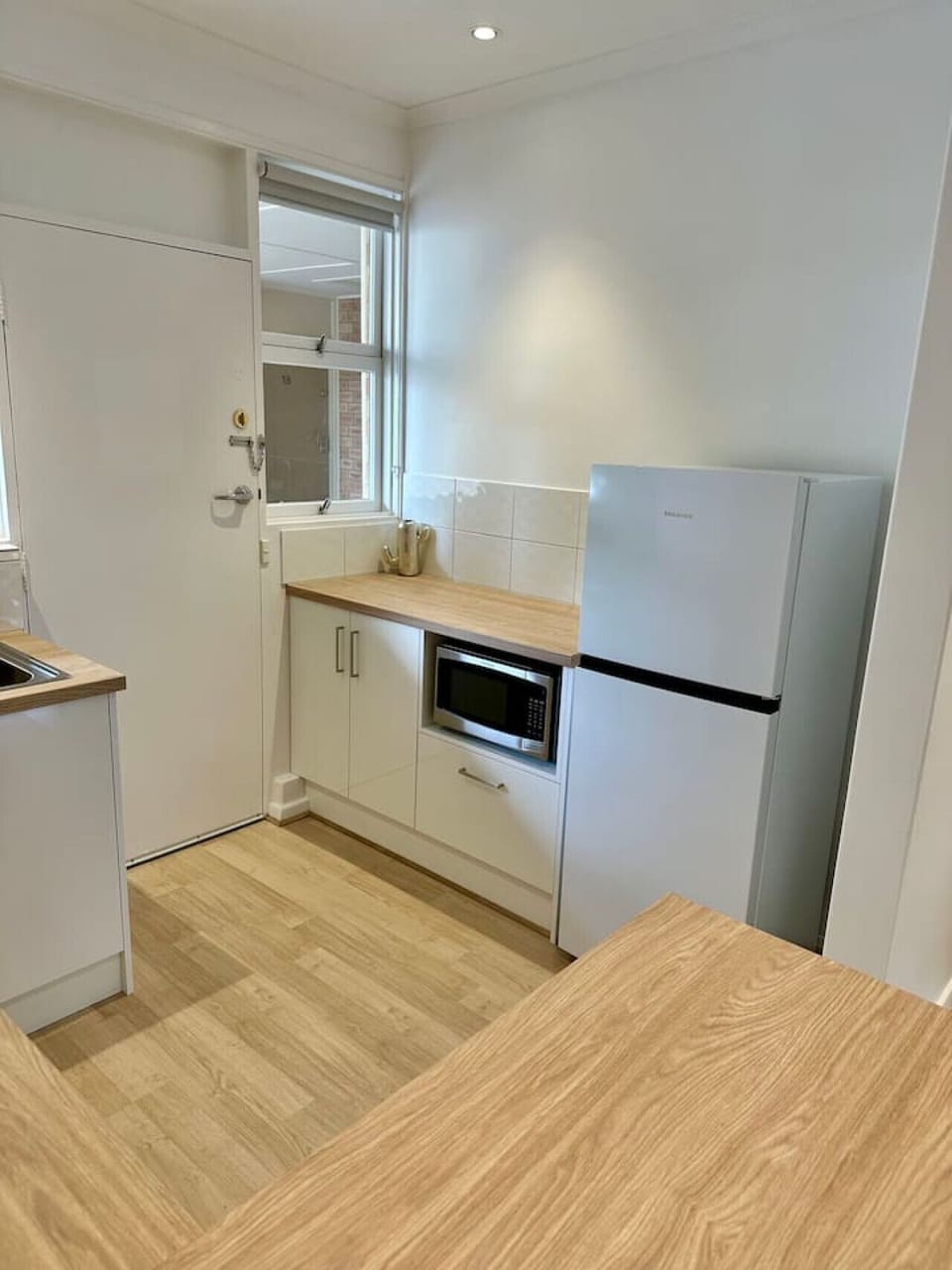 Functional setup featuring a full-size fridge, microwave, and plenty of bench space.