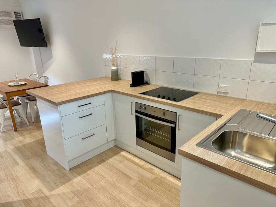 Compact kitchen corner with modern appliances and light timber bench tops.