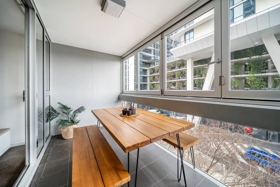 Enjoy morning coffee or an easy evening meal on the enclosed balcony, where timber bench seating creates a relaxed perch above the city streets.