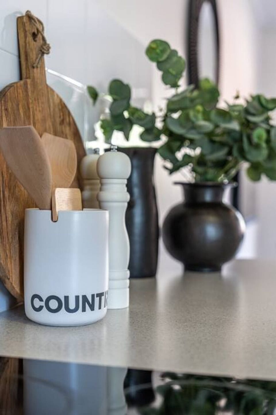 Chopping boards, utensils and a touch of greenery bring warmth to the bench space.