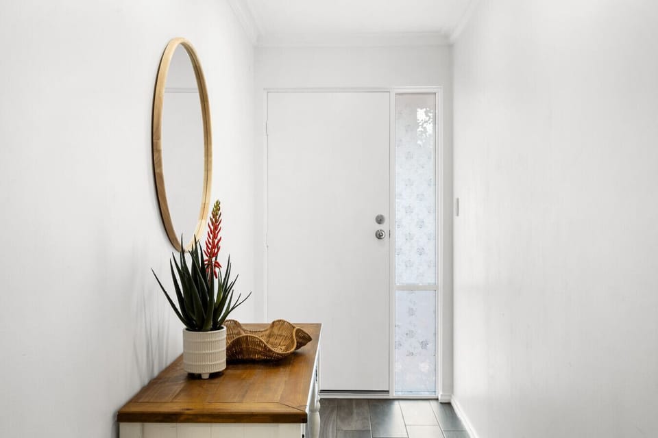 Step through the private entryway into a bright, air-conditioned interior where coastal tones, timber textures, and natural light immediately set a relaxed holiday mood.