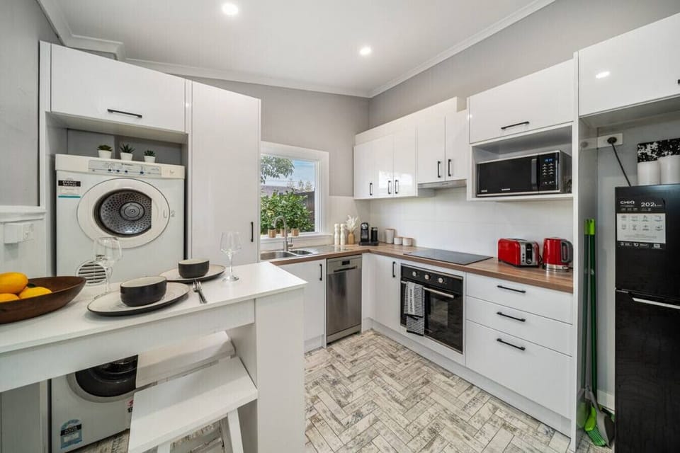 Enjoy the convenience of a full laundry tucked into the cabinetry, with a washer, dryer, iron, and drying rack ready for use.