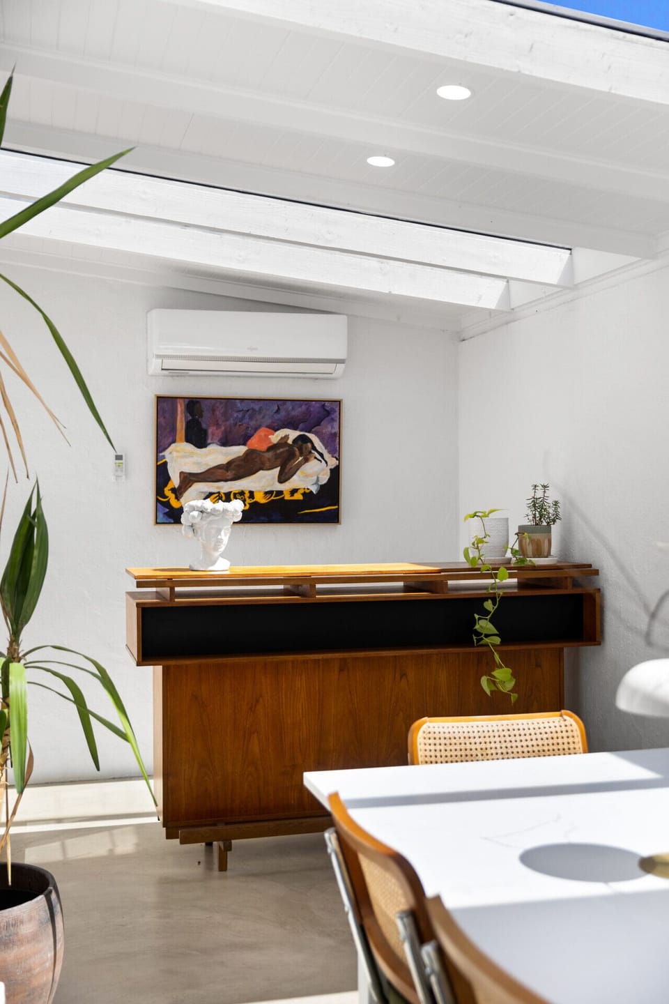 Set beneath bright skylights, the bar beside the dining table creates a stylish nook for serving drinks and elevating shared meals.